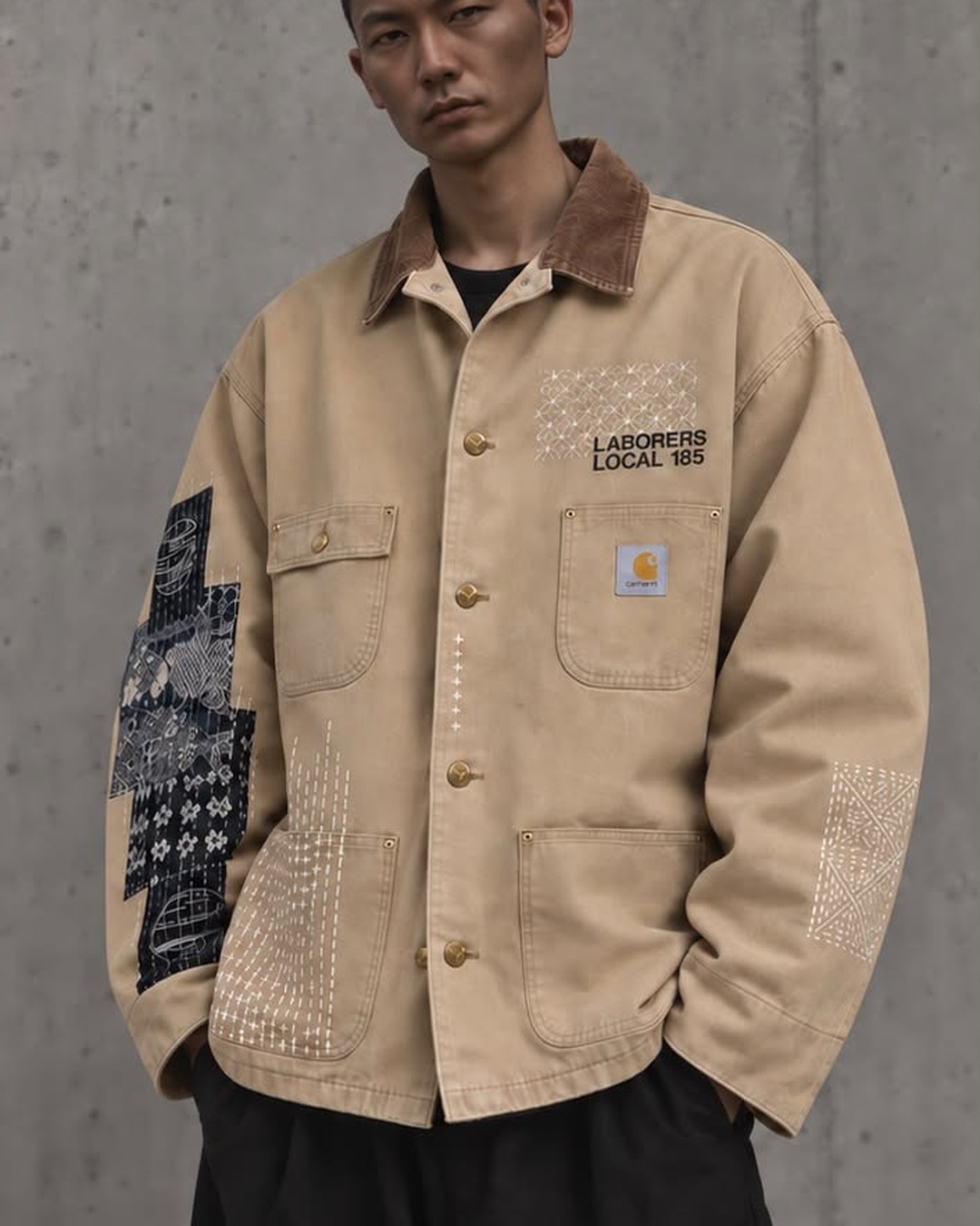 Front view of the tan jacket with visible stitching at the chest, pocket, cuff and sleeve.